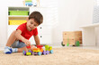 © New Africa - Cute little boy playing with colorful toys on floor at home, space for text