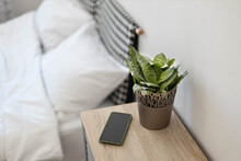 Smartphone on bedside table with bed in the background