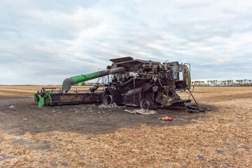 Back/Side View of Burnt Combine Harvester on Grain Field in Rural North Dakota, taken at Daytime with Cloudy Sky.