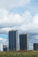 Construction of modern multi-storey buildings. New development of a residential area. House frames, construction cranes and building materials at the construction site.