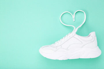 Wall Mural - White shoe and shoelaces in shape of heart on mint background