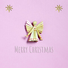 Christmas card with Christmas angel made of straw. Straw Christmas ornament and Christmas greeting on pink background