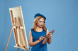 © SHOTPRIME STUDIO - Woman artist blue beret drawing palette easel hobby creativity blue background
