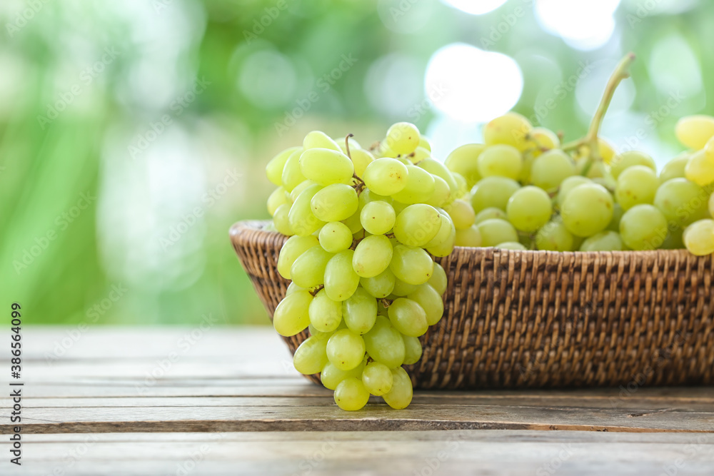 Wicker bowl with ripe grapes on table outdoors