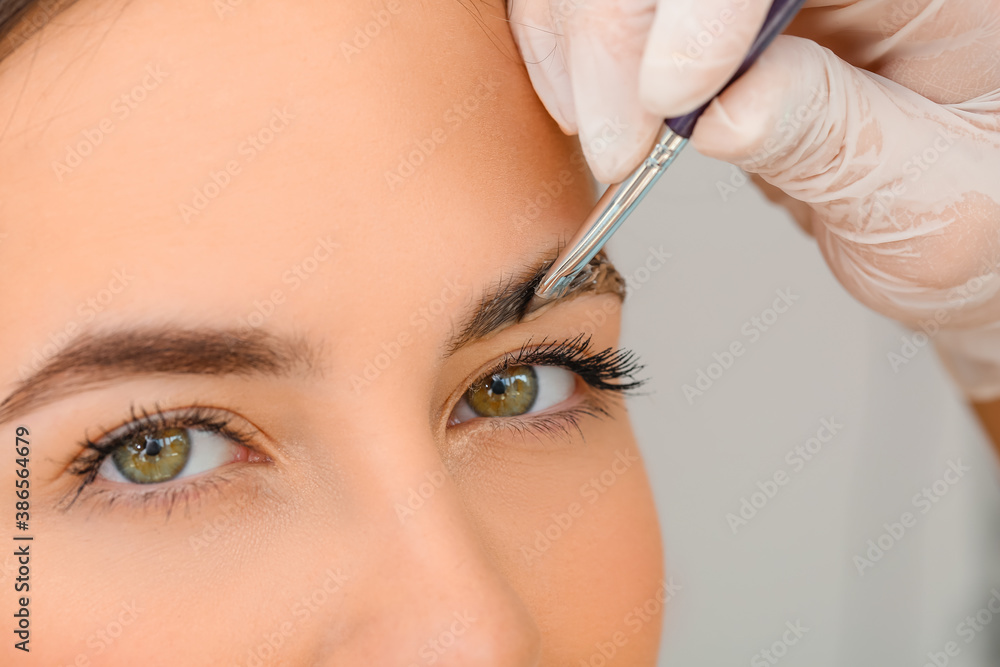 Young woman undergoing eyebrow correction procedure in beauty salon, closeup