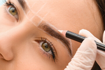 Young woman undergoing eyebrow correction procedure in beauty salon, closeup