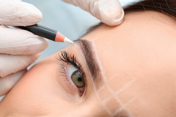 Young woman undergoing eyebrow correction procedure in beauty salon, closeup