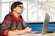 © Stanislaw Mikulski - Old woman works (learning to work) on laptop in her house.