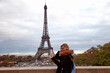 © astrosystem - Girl using cellphone with Paris city background and Eiffel tower.