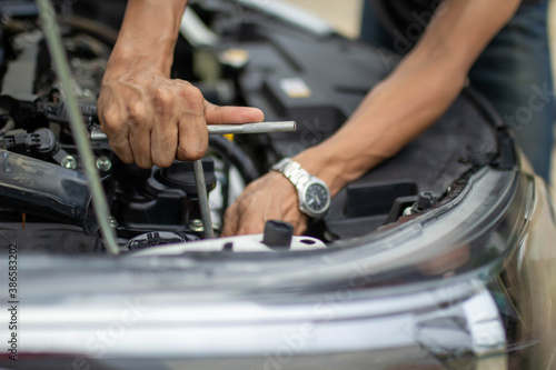 Automobile mechanic repairman hands repairing a car engine automotive workshop with a wrench, car service and maintenance.