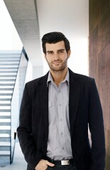 Canvas Print - Portrait of handsome confident businessman standing with hand in pocket, looking at camera.