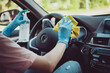Cropped photo of driving teacher girl sit car wash rag disinfect antiseptic bottle steering wheel before student come ride learn wear blue latex gloves in city center