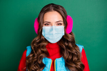 Poster - Photo of cute lovely young lady wear medical mask pink ear warmers blue vest red pullover isolated green color background