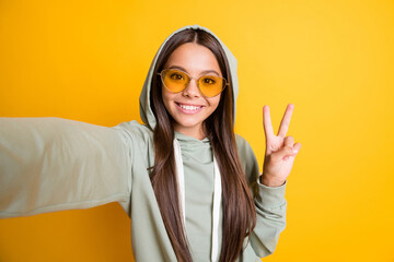 Canvas Print - Photo of beautiful brunette hair kid show arm finger v-sign on selfie hoodie isolated on yellow color background