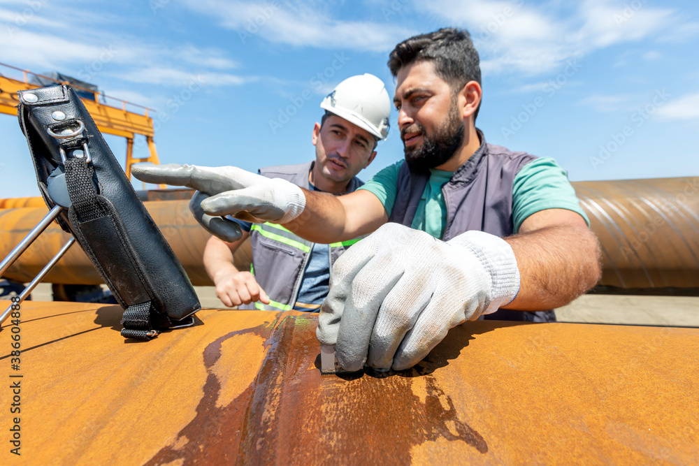 Non-destructive testing technicians are checking welds of pipe with ...
