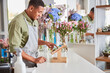 © Viacheslav Yakobchuk - Joyful young man working as cashier at florist