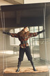 © monchak - full length photo of a girl with curly brown hair dressed in checkered jacket, leather gloves and black pants, she is standing on a swing in a loft studio holding on to a chain from a swing