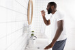 side view of afro-american man drinking water and looking in mirror