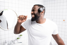 Afro-american Man With Headphones Singing In Toothbrush