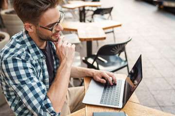 Serious young man working on laptop computer