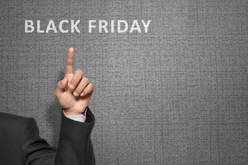 Wall Mural - Businessman pointing something Black Friday text with hand on a textured background