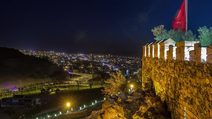 Wall Mural - Aerial view from old castlethe in historical city town of Nevsehir night timelapse. Panoramic skyline with illuminated flag and walls with lights