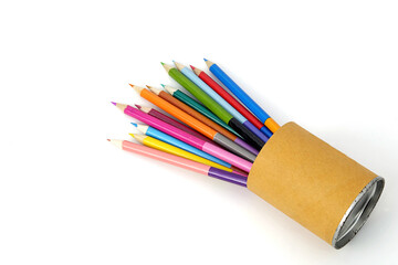 Group of coloured pencils in a cardboard glass on a white background.