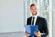 © GVS - Handsome smiling businessman with clipboard in a bright modern office