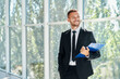 © GVS - Handsome smiling businessman with clipboard in a bright modern office