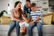 © JustLife - Young family enjoying at home. Mother and father tickling son.