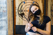 © Mat Hayward - Teenage girl holding axe at an axe throwing range with target behind her