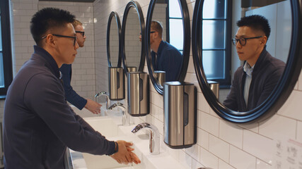 diverse men washing hands in washroom sink of business center or restaurant