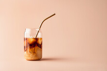 Glass Of Iced Coffee In Tall Glass With Golden Straw With Cream On Pastel Background For Your Design. Food Concept In Vintage Style. Copy Space. Closeup.