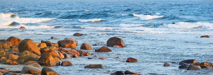 Wall Mural - Panoramic view of the Baltic sea shore, Hiiumaa island, Estonia. Soft sunset light. Stones, waves and water splashes close-up. Travel destinations, nature, eco tourism