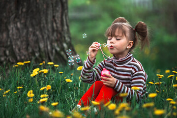 Wall Mural - Little cute girl blowing soap bubbles in the park.