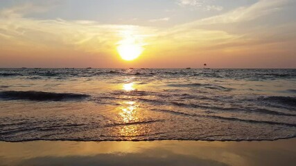 Wall Mural - Beautiful Colorful Sunset Over Indian Ocean, low large orange Sun, slow calm waves, tropical sandy beach with sky and clouds for travel in holiday relax time, fishing boats at horizon line