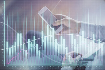 Double exposure of man's hands holding and using a digital device and forex graph drawing. Financial market concept.