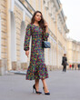 © Dmitry Tsvetkov - Elegant woman in dress walking city street on fall or autumn day. Pretty girl with long wavy hair holding handbag
