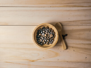 Wall Mural - coffee beans in  wood bowl top view on wooden table for food content.