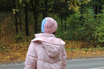 Girl in a warm 2-colored hat, autumn forest