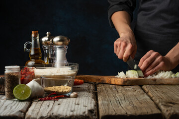 Rustic wooden table with ingredients for cooking on professional chef cuts onion background. Concept of preparing healthy meal. Close-up view.