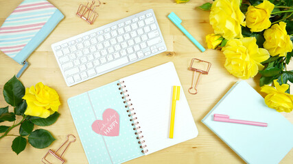 Wall Mural - Modern feminine pink, blue and yellow theme desktop workspace with yellow roses on stylish pale wood background. Top view blog hero header creative composition flat lay.