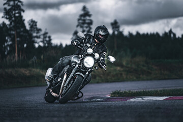 man riding motorcycle in asphalt road. Motorcyclist at black and white sport motorcycle