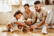 © JenkoAtaman - Diverse parents playing with son in kitchen.