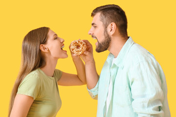 Wall Mural - Young couple with sweet donut on color background