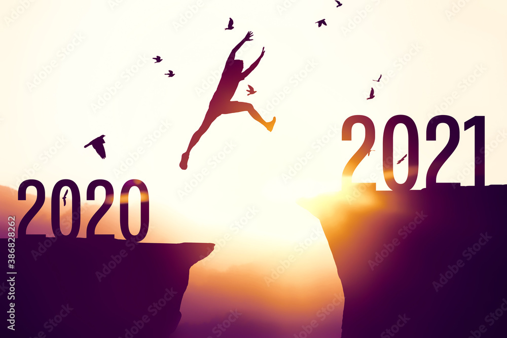 Silhouette man jumping between cliff with number 2020 to 2021 at tropical sunset beach. Freedom challenge and travel adventure holiday concept. - obrazy, fototapety, plakaty 