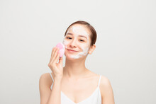 Young Woman Using Facial Cleansing Brush On White Background, Closeup. Washing Accessory