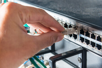 hand of engineer plugging in ethernet cable into server switch