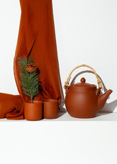 Wall Mural - Clay teapot and brown textille decor in white trendy space. Still life scene. Winter time christmas concept