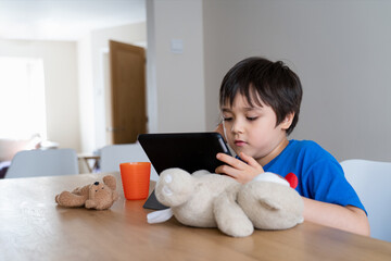 Kid self isolation using tablet for his homework,Child using digital tablet searching information on internet at home,Home schooling,Distance education,E-learning online education with new normal life